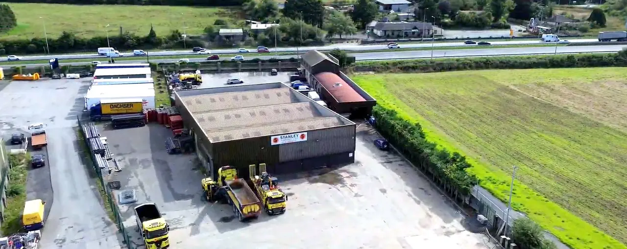 The Stanley Asphalt yard from the air: the depot, its yellow tippers and the motorway beyond.